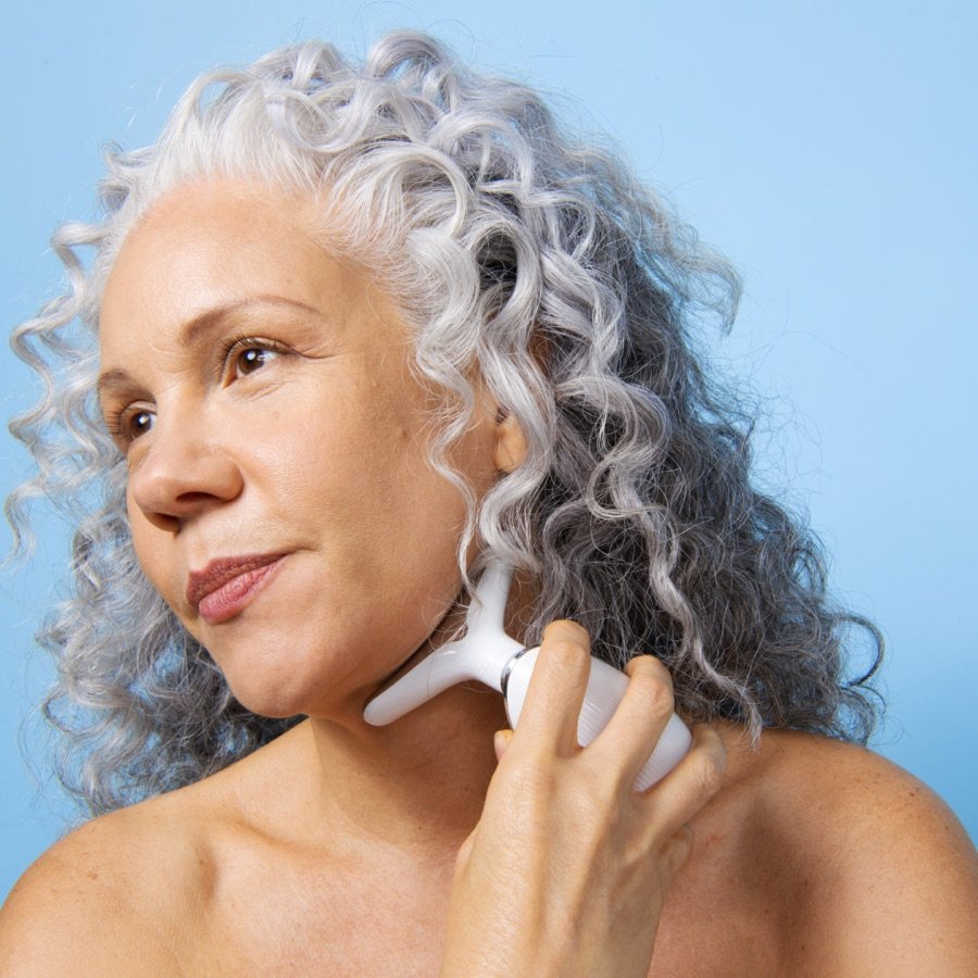Woman using the MyoGlow LED device along her neck (official brand photo)